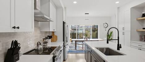 A modern kitchen with white cabinetry, a central island, and a view to the outside.