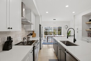 A modern kitchen with white cabinetry, a central island, and a view to the outside.