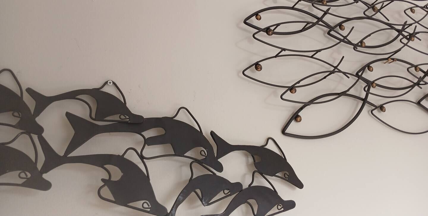 A wall with a decorative metal fish sculpture.
