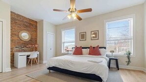 A bedroom with a bed, a desk, a chair, a ceiling fan, and two windows. - East End Pittsburgh 4 Bedroom Getaway (Pittsburgh)