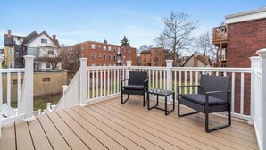 A wooden deck with two black wicker chairs and a small table, surrounded by a white railing. - East End Pittsburgh 4 Bedroom Getaway (Pittsburgh)