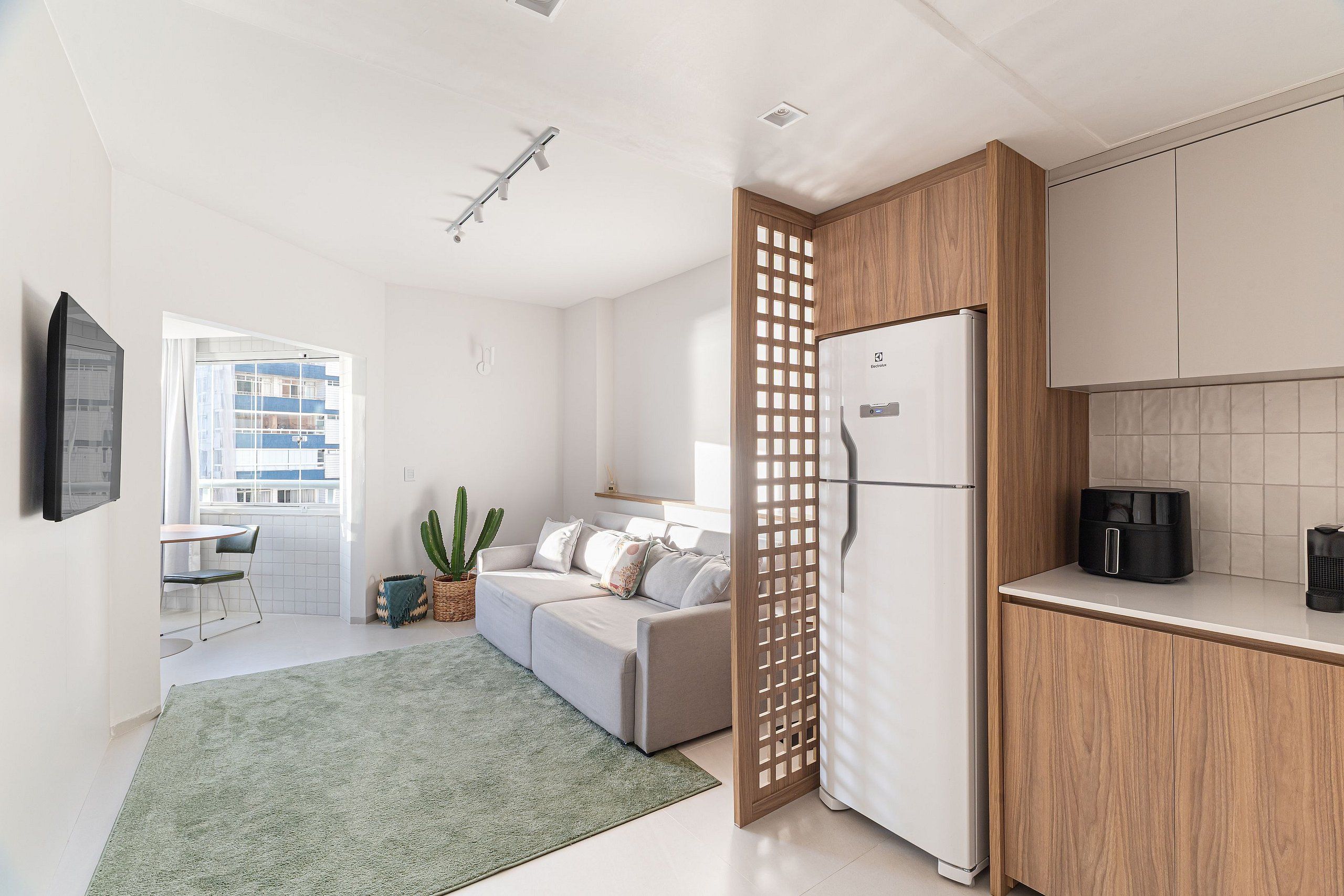 Una cocina moderna con refrigerador, armarios de madera y un comedor con mesa y sillas.