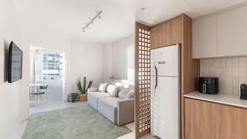 Una cocina moderna con refrigerador, armarios de madera y un comedor con mesa y sillas.