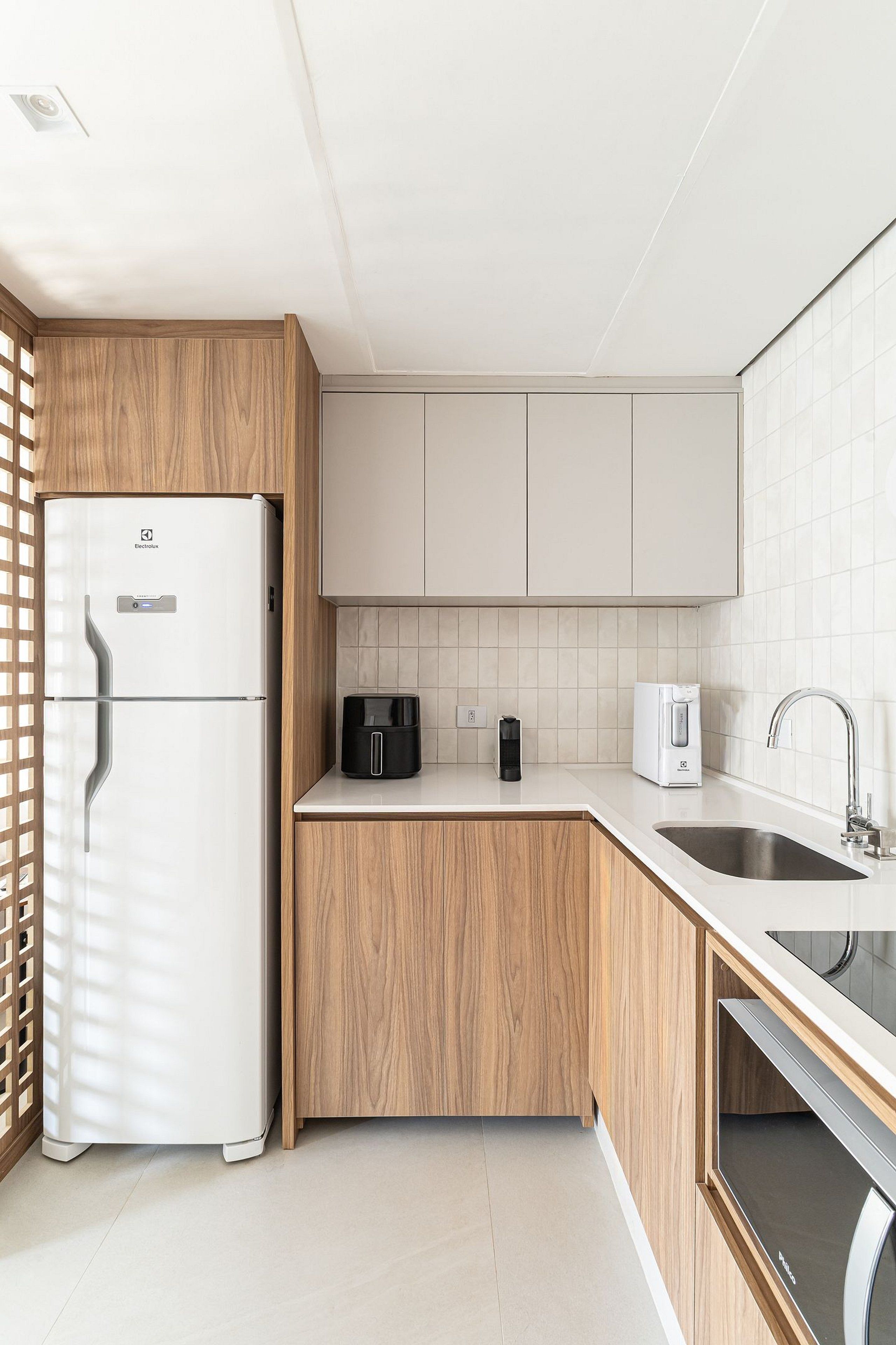 A modern kitchen with a refrigerator, coffee maker, and sink.
