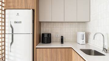 A modern kitchen with a refrigerator, coffee maker, and sink.