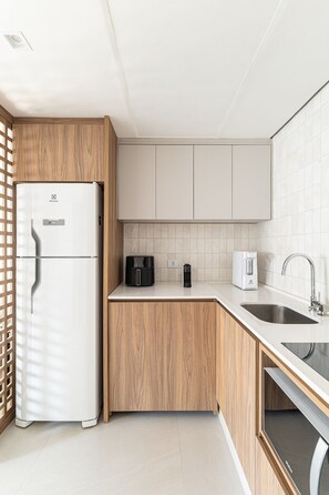 A modern kitchen with a refrigerator, coffee maker, and sink. - ARK Houses - Flat Luxo Vista-Mar c/ Piscina na Cobertura (Santos)