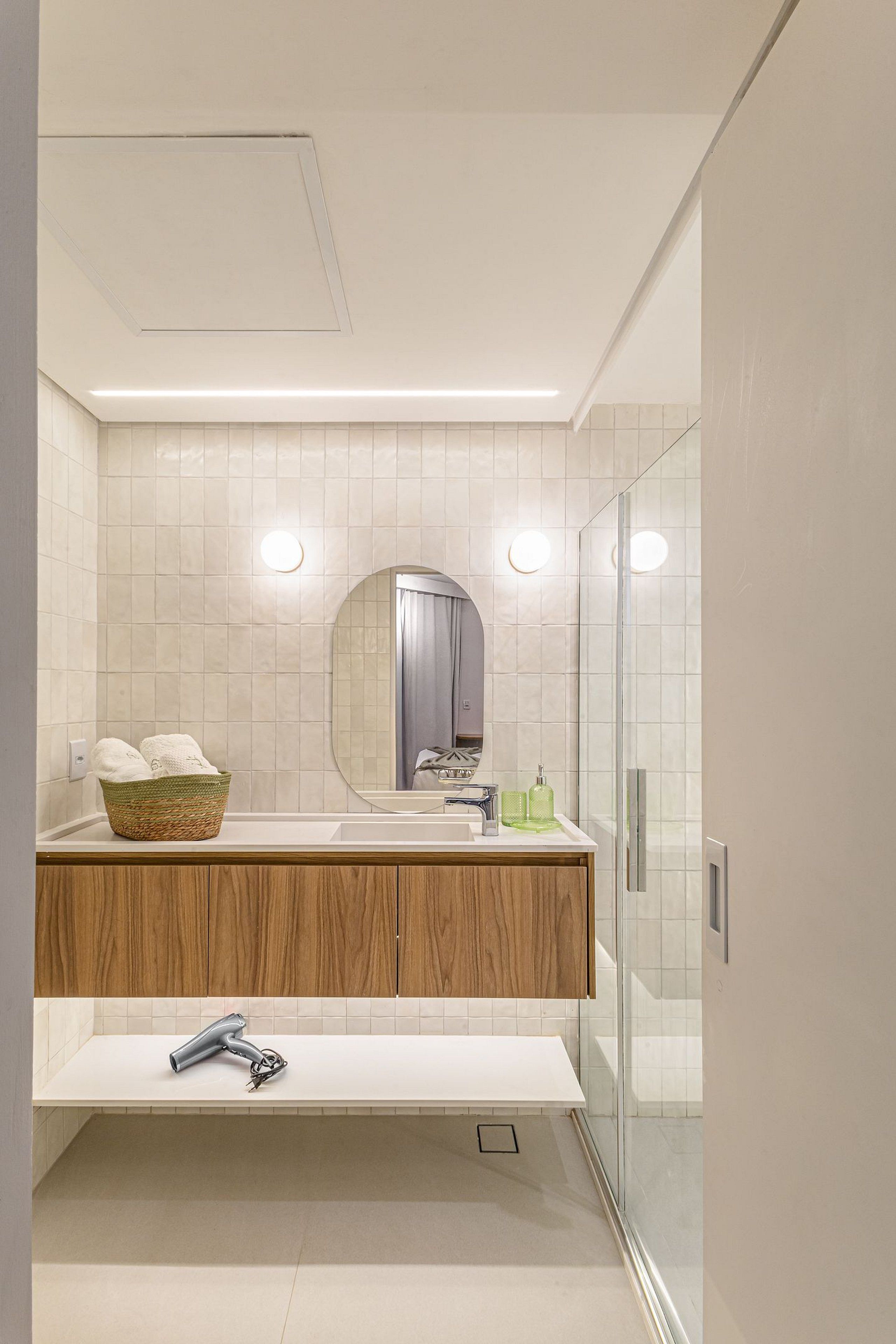 A modern bathroom with a white sink, wooden vanity, a mirror, and a glass shower enclosure.