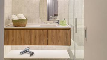 A modern bathroom with a white sink, wooden vanity, a mirror, and a glass shower enclosure.