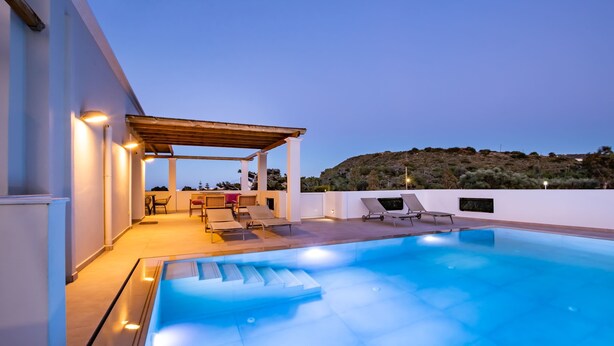 Un área de piscina en la azotea con sillones de descanso y una pérgola.