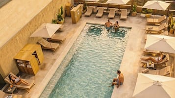 Una piscina al aire libre, camas de piscina con cargo, sombrillas