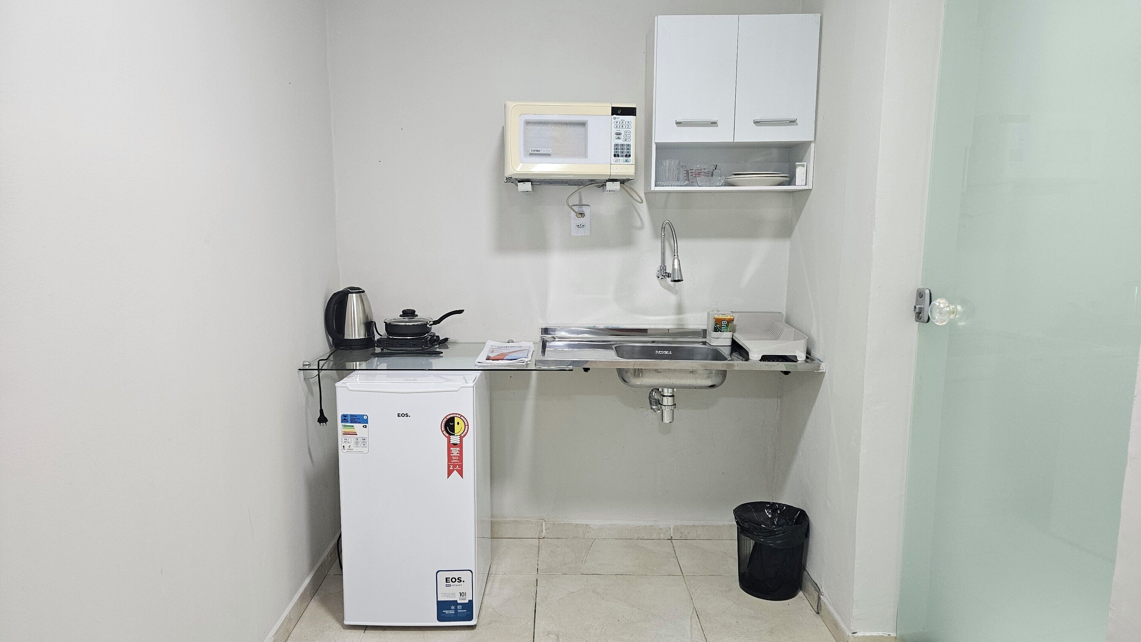 A compact kitchenette with a refrigerator, microwave, sink, and a small cabinet.