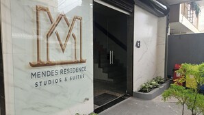 A building entrance with a sign for 'Mendes Residence Studios & Suites'.