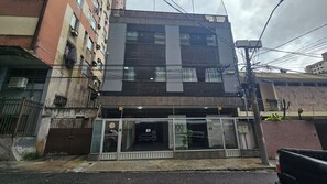 Un bâtiment à deux étages dont le rez-de-chaussée est aménagé en espace commercial, comprenant un magasin avec des portes vitrées et une enseigne bien visible.
