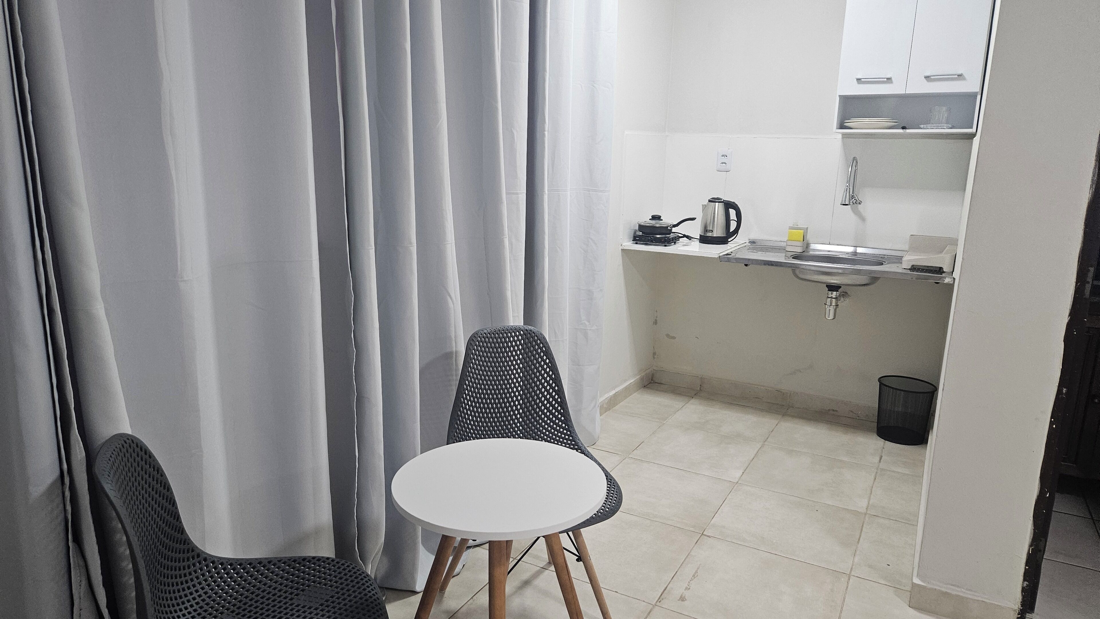 A small kitchenette with a sink, a kettle, and a coffee maker. There is a round table with two chairs.