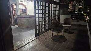 An outdoor seating area with two wicker chairs and a tiled floor.
