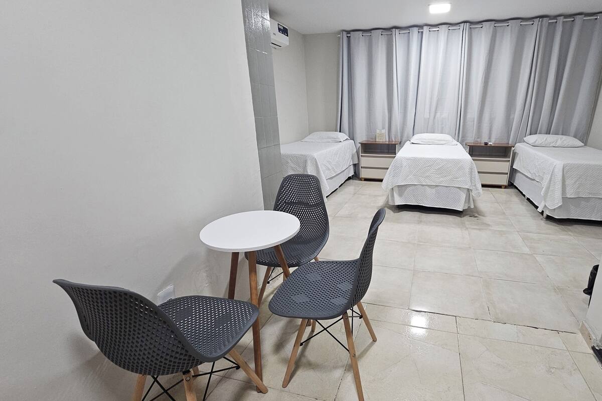 A hotel room with two single beds, a small round table, and two chairs.