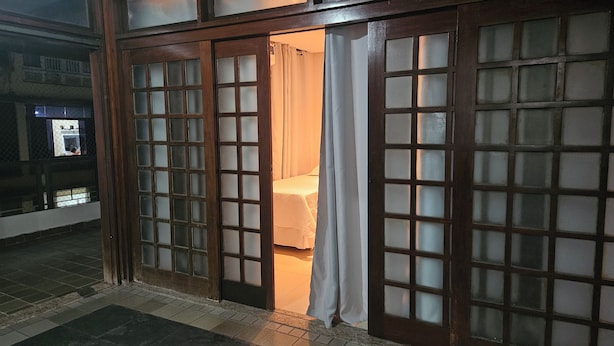 A room with a bed, a curtain, and a wooden door with glass panels.