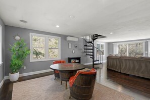 A modern interior with a round table, chairs, a spiral staircase, and a large window.