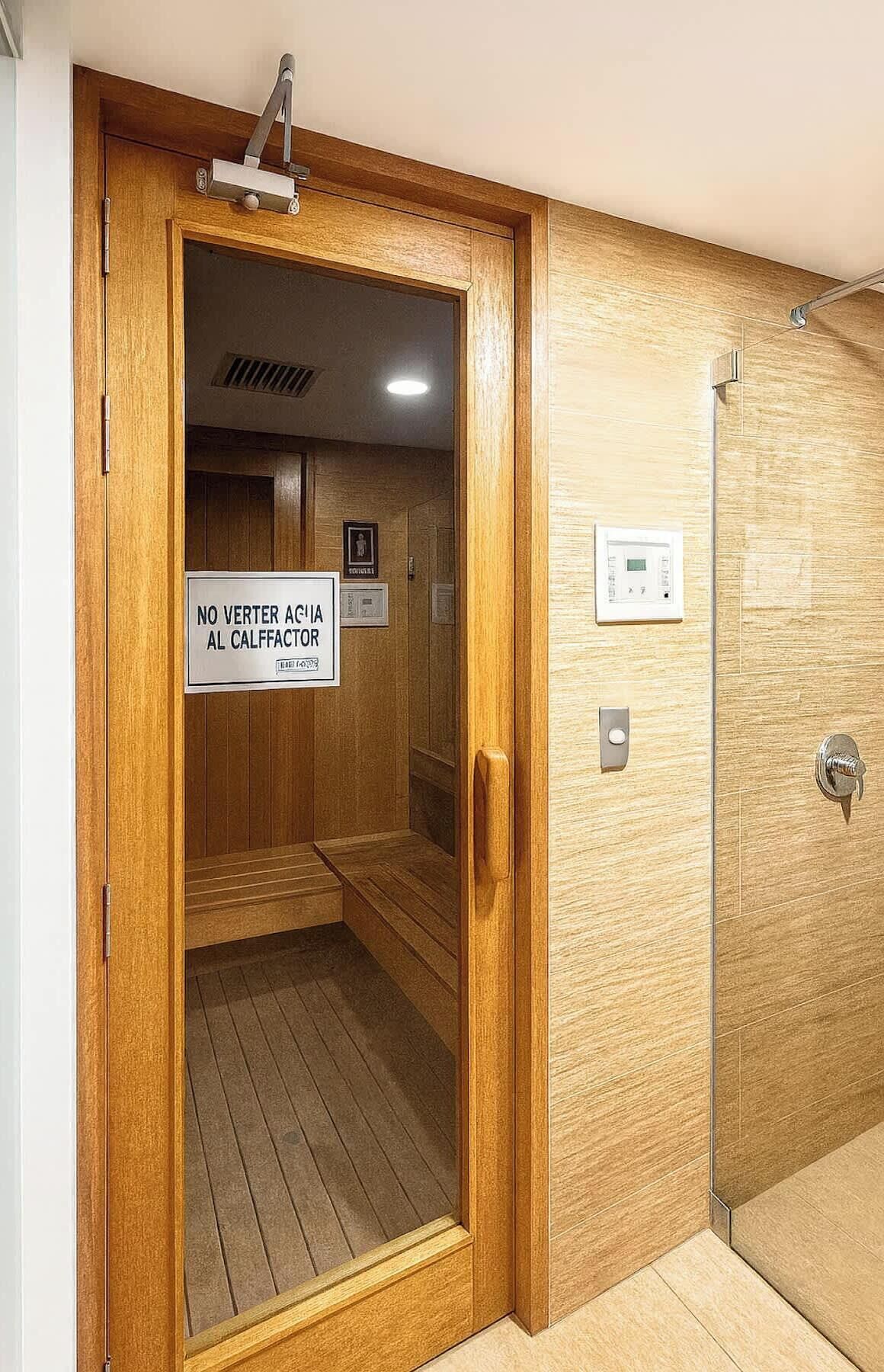 A wooden door with a sign that reads 'NO VERTER A CIGARETTE AL CALFFACTOR' and a shower area with a control panel.