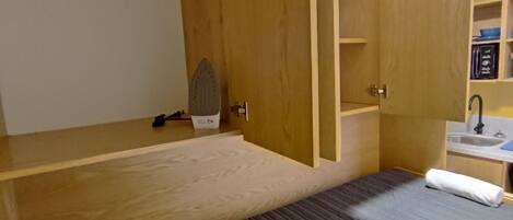 Una habitación compacta con una cama, un escritorio pequeño y una estantería empotrada.