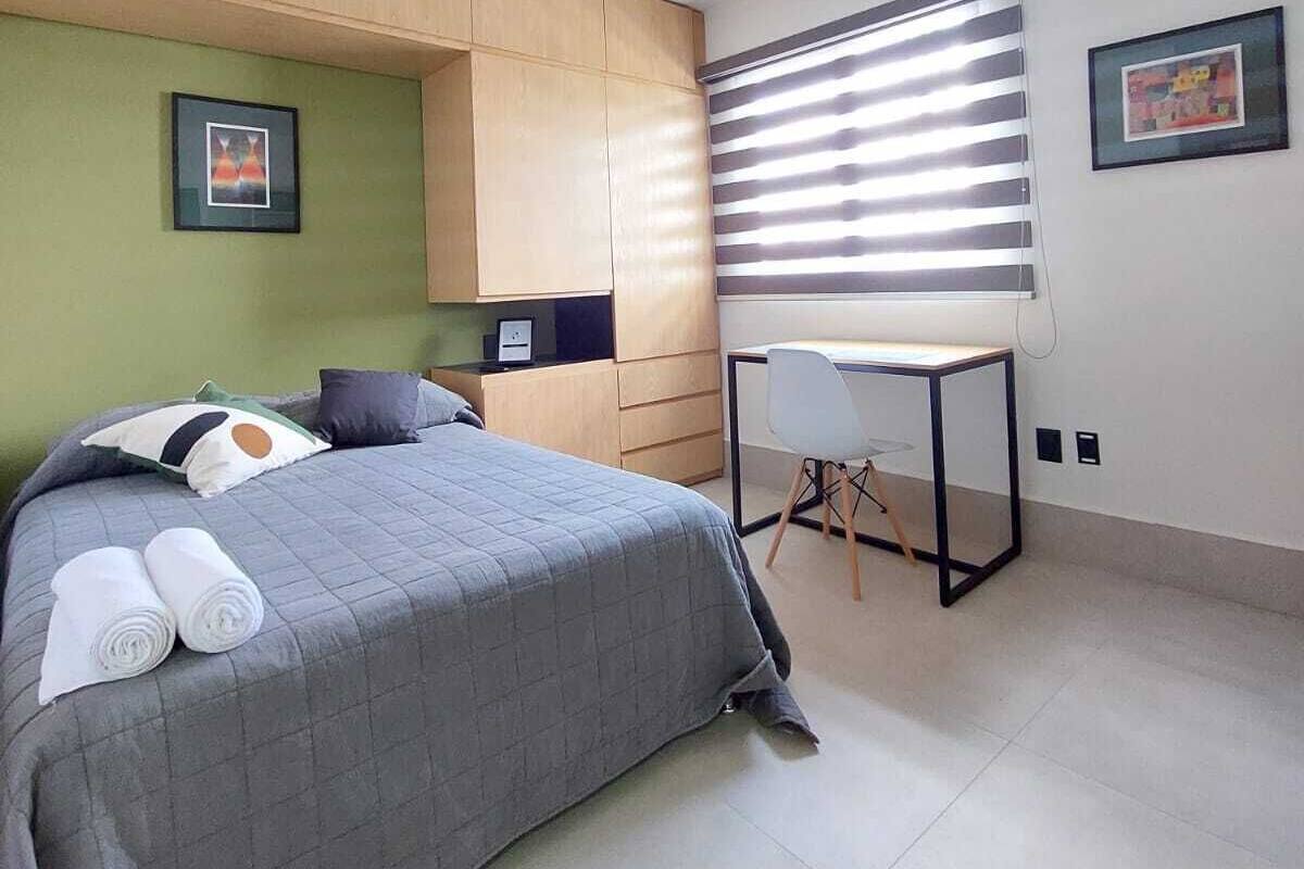 A modern bedroom with a bed, a desk, and a chair.