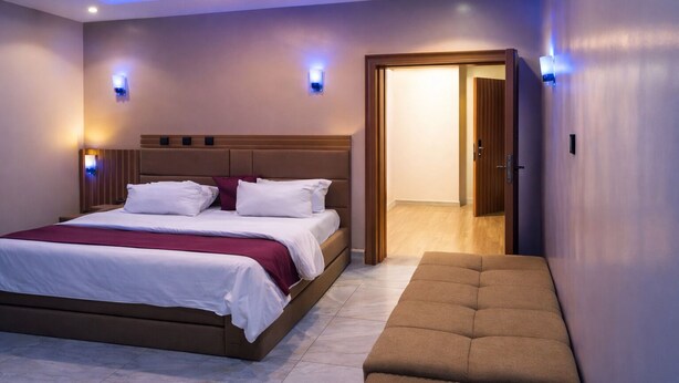 Un dormitorio moderno con una cama grande, lámparas de noche y un banco.