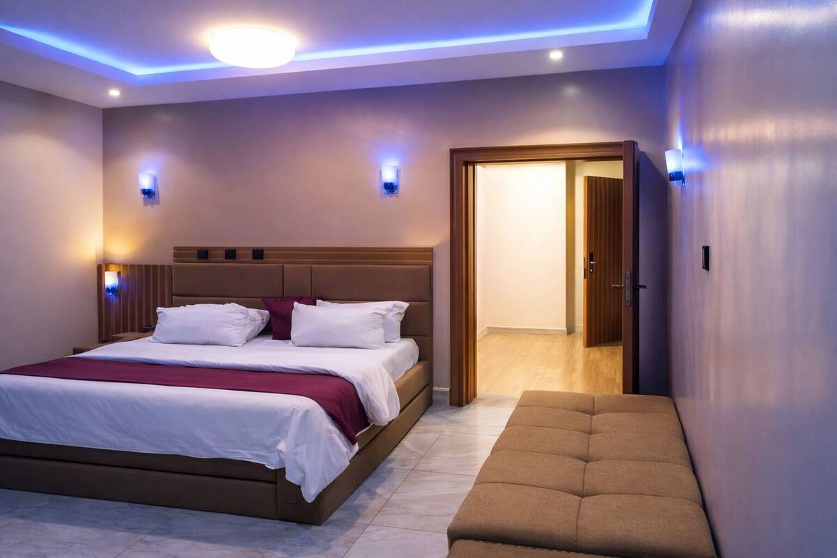 Un dormitorio moderno con una cama grande, lámparas de noche y un banco.