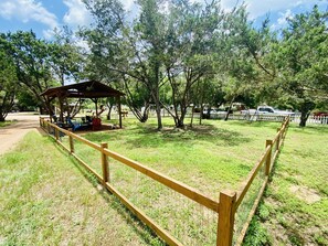 Un parc doté d’une clôture en bois, de tables de pique-nique et d’un espace de repos abrité.
