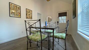 Ein Essbereich mit einem Holztisch und -stühlen, botanischen Drucken an der Wand und einem Fenster mit Jalousien.