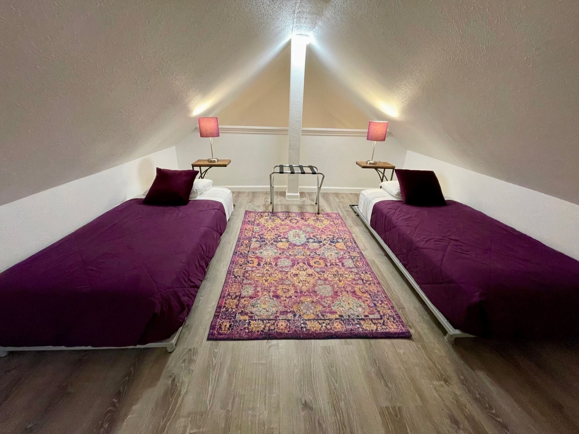 A room with two beds, a central rug, and a ceiling light.