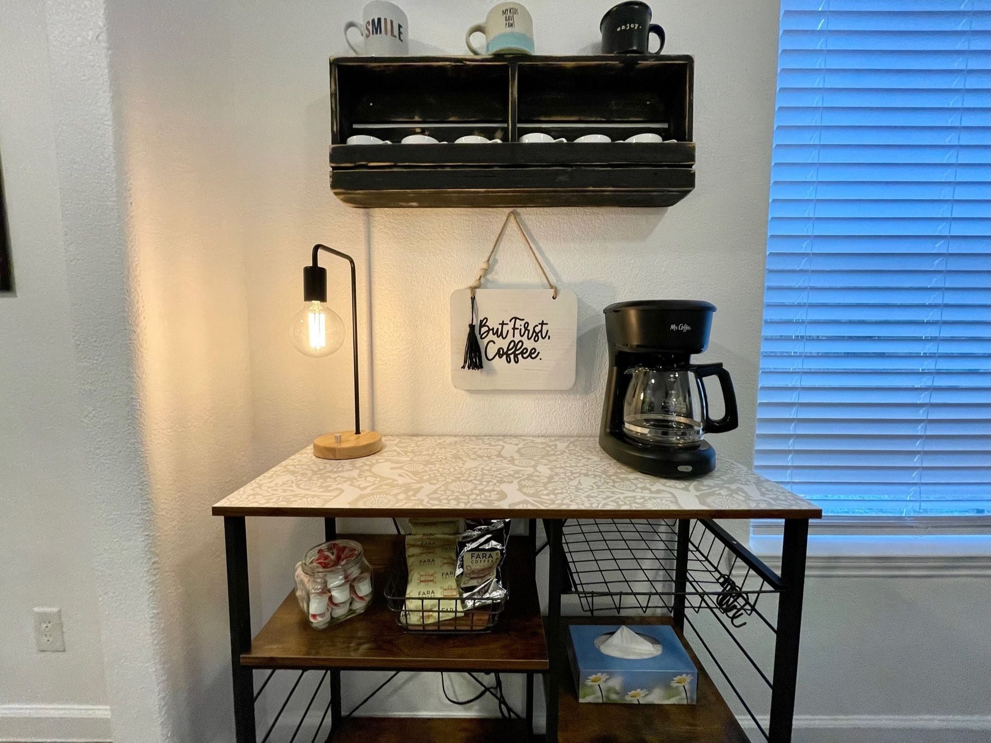 A kitchen counter with a coffee maker, a hanging sign, and a light fixture.