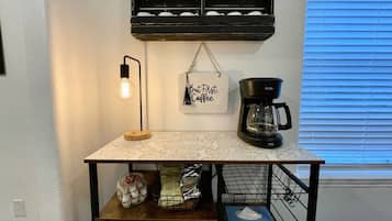 A kitchen counter with a coffee maker, a hanging sign, and a light fixture.
