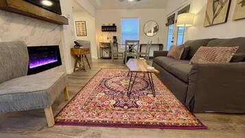 A living room with a fireplace, a sofa, a coffee table, and a patterned rug.