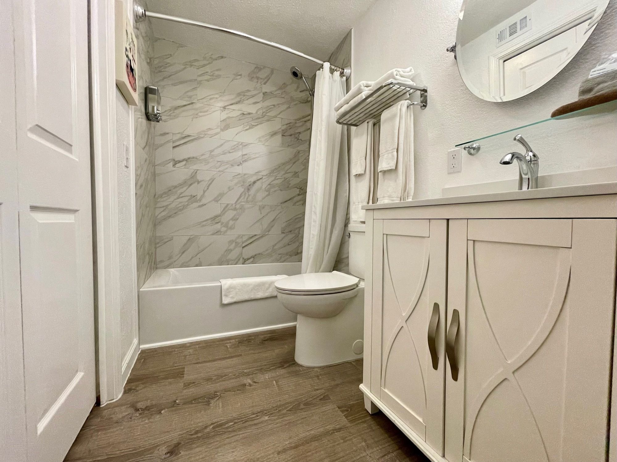 A bathroom with a bathtub, toilet, and vanity with a mirror.