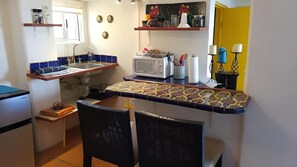Ett kompakt kök med diskho, mikrovågsugn och en liten matplats med stolar.