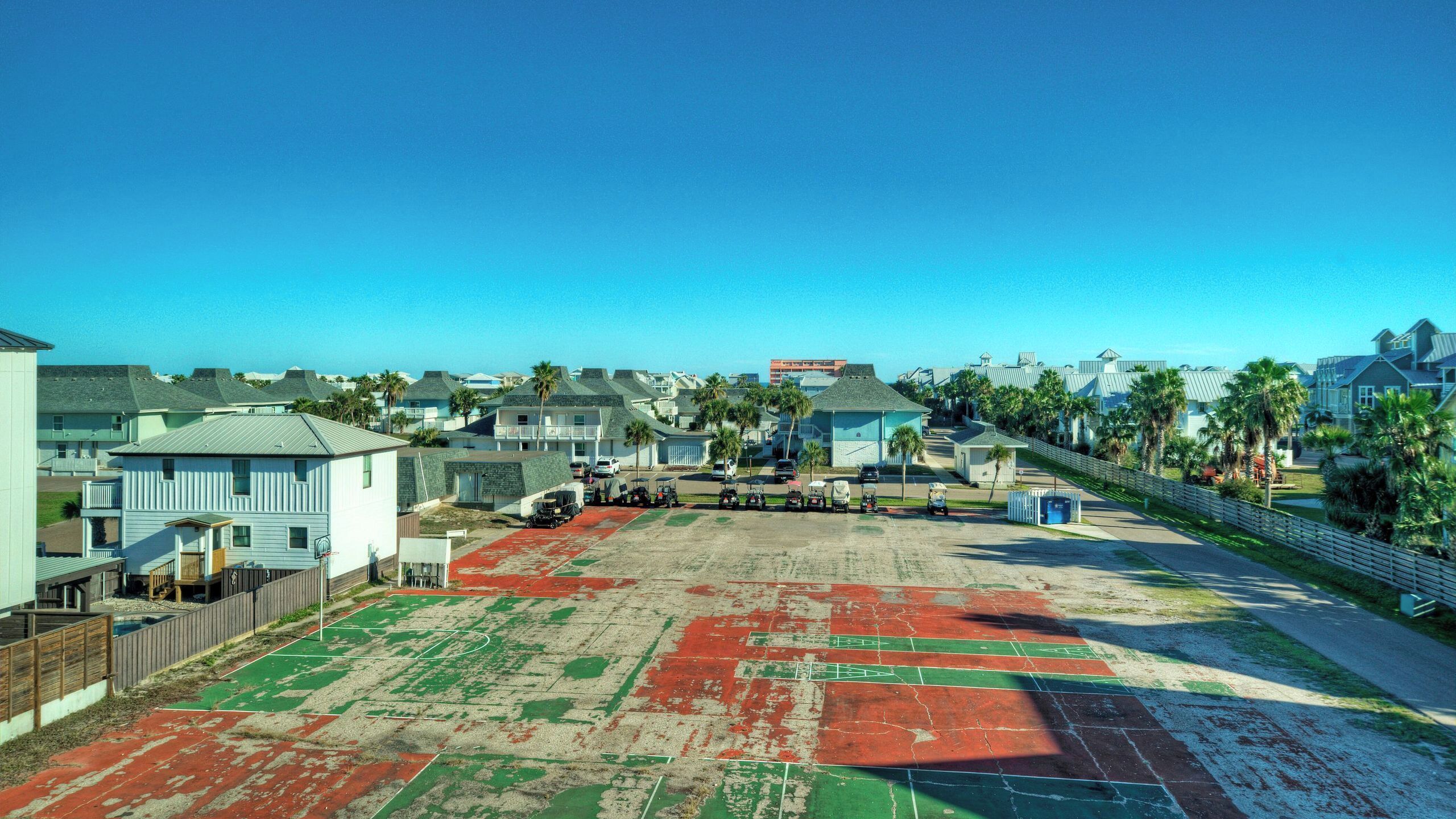 A coastal residential area with houses, a clear sky, and a sports field.