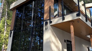A modern two-story house with large windows, a flat roof, and a wooden deck. - Brand new spa resort style waterfront  executive home with luxury amenities (SALT SPRING ISLAND)