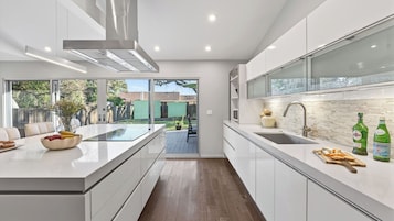 Una cocina moderna con una isla central, horno empotrado y un amplio ventanal con vistas al jardín.