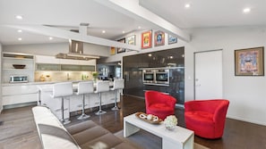 A modern kitchen with a central island, bar stools, and a red armchair. - Ripple by Avantstay Private Pool + Pickleball Court + Firepit Exclusive Sonoma Valley Retreat (Sonoma)