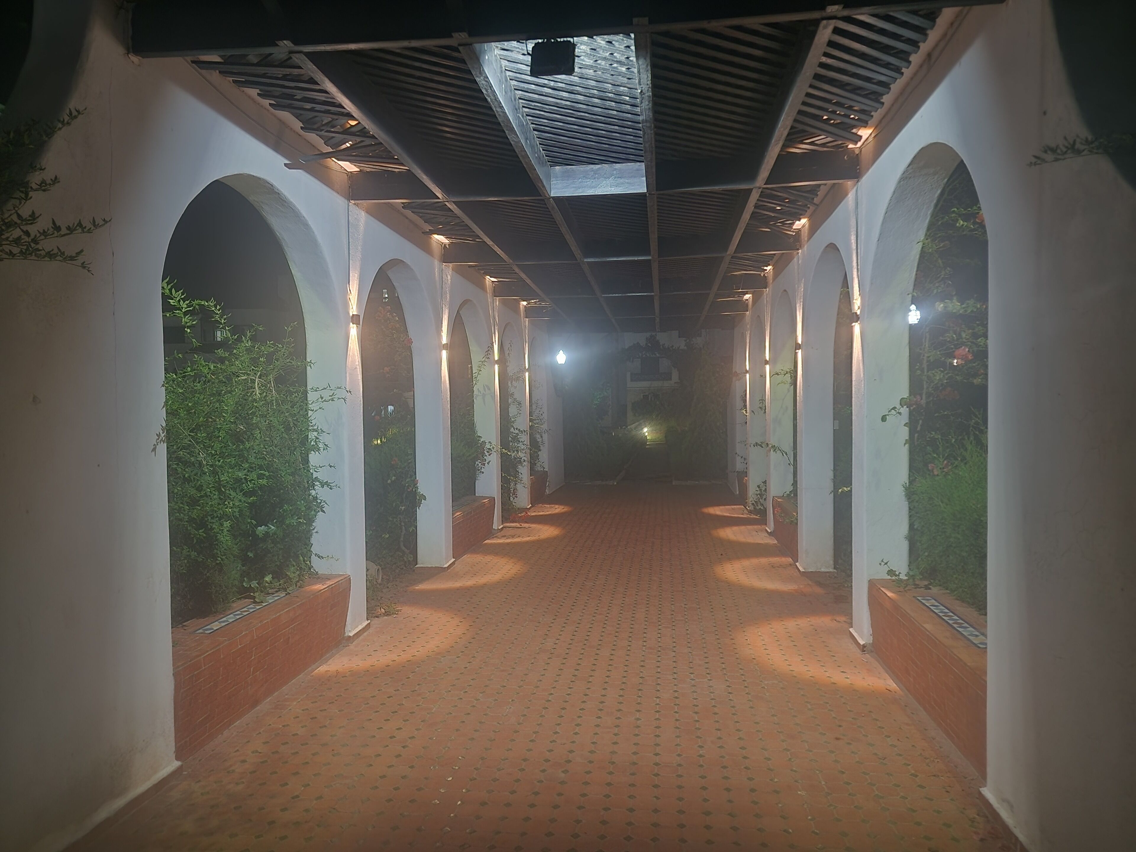 A corridor with arched ceilings and a patterned floor, leading to a dimly lit area.