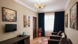 A living room with a sofa, TV, and artwork on the walls. - Golden Street Hotel (Baku)