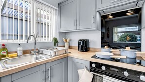 Una cocina moderna con gabinetes grises, un lavamanos de acero inoxidable, una cafetera y una estufa.