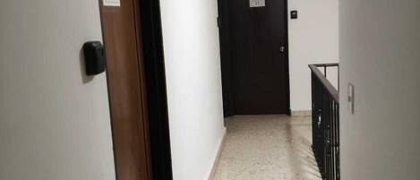 Un pasillo estrecho con una puerta de madera con el número '09' y otra puerta negra con el número '11'.