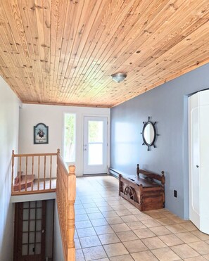 A room with a wooden ceiling, a bench, a wall-mounted mirror, and a door.