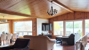 A spacious living area with a wooden ceiling, a sofa, a coffee table, and a TV.
