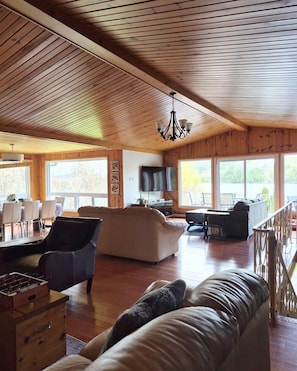 A spacious living area with a wooden ceiling, a sofa, a coffee table, and a TV.
