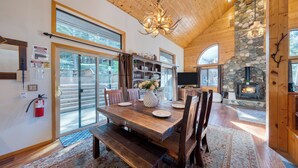 Un comedor amplio con una mesa de madera, bancos y una chimenea de piedra.