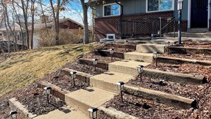 A residential building with a brick facade, a front porch, and a set of concrete steps leading to the entrance. - Cozy 2BR ~15 minutes to Red Rocks (Denver)