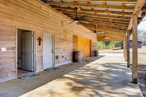 Une cabane en bois dotée d’un porche couvert, d’un ventilateur de plafond et d’une porte donnant sur un espace intérieur.