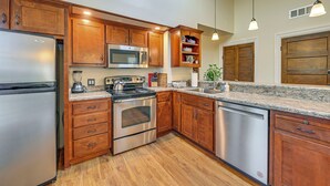 A kitchen with wooden cabinets, stainless steel appliances, granite countertops, and pendant lighting. - Bourbon Country Escape! Spacious Home w/ Fire Pit (Taylorsville)